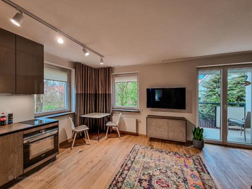姆拉哥沃Apartament VIP PROMENADA的厨房设有带桌子和电视的客厅。