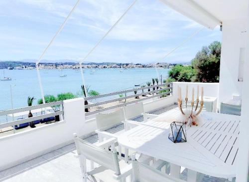 波多河丽Fairy home Porto Heli的俯瞰水面的阳台配有白色的桌椅