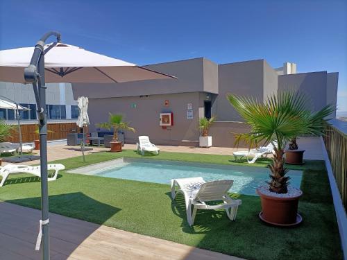 马德里Hotel BESTPRICE Alcalá的一个带椅子、棕榈树和遮阳伞的游泳池