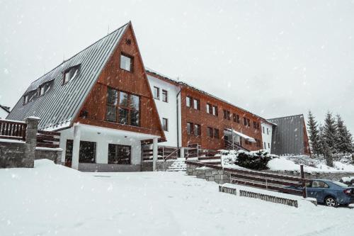 小莫拉夫卡Horský hotel Brans的雪地里停着汽车的建筑物