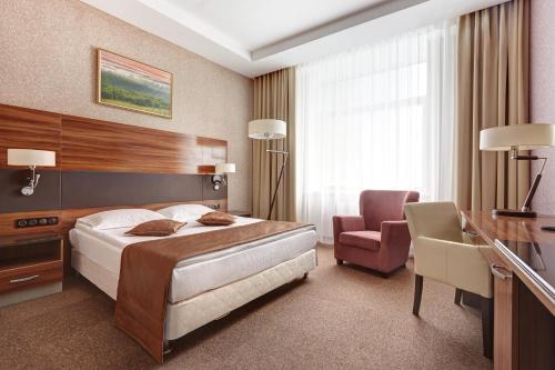明斯克明斯克维多利亚奥林匹克酒店及商务中心的一间卧室配有一张床、一张桌子和一把椅子