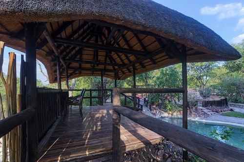 OtjovasanduHobatere lodge的一个带茅草屋顶的木甲板和一个游泳池