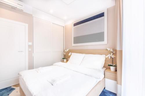 尤斯托尼莫斯基VacationClub - Boulevard Residence Apartament 11的卧室配有白色的床和窗户。