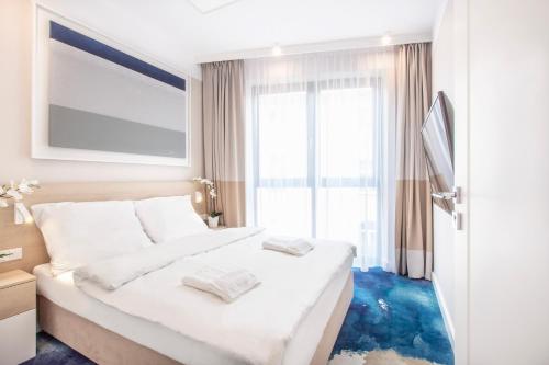尤斯托尼莫斯基VacationClub - Boulevard Residence Apartament 11的卧室配有白色床,铺有蓝色地板