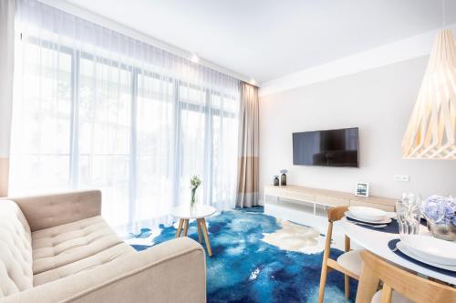 尤斯托尼莫斯基VacationClub - Boulevard Residence Apartament 11的一间铺有蓝色地毯的客厅
