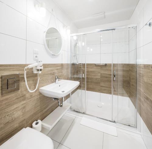 尤斯托尼莫斯基VacationClub - Boulevard Residence Apartament 11的带淋浴和盥洗盆的白色浴室