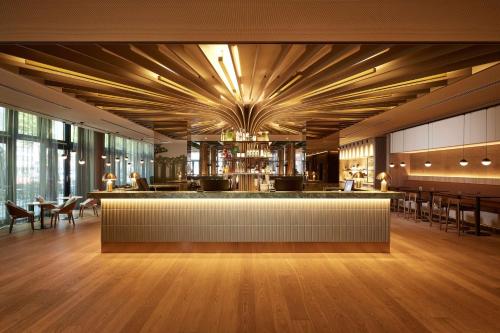 杜塞尔多夫Adina Apartment Hotel Dusseldorf的餐厅设有酒吧,配有桌椅