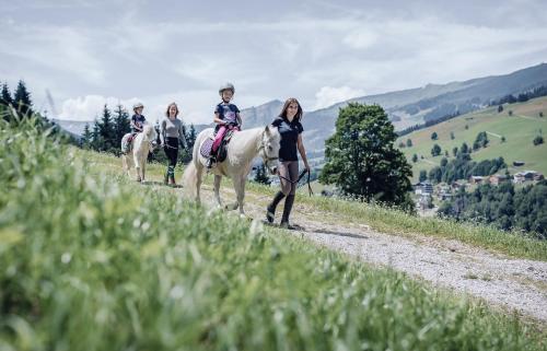 萨尔巴赫Familienresort Ellmauhof - das echte All Inclusive的三个孩子骑在土路上骑马