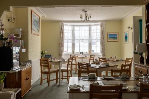 韦茅斯海浪旅馆的一间带桌椅的用餐室和窗户。