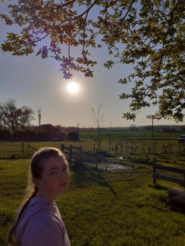 Tieltsheepinn hoekje的站在阳光下田野上的年轻女孩