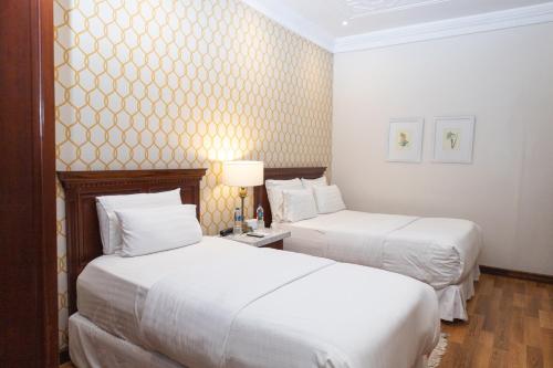 昆卡圣卢西亚精品酒店的配有白色床单的酒店客房内的两张床
