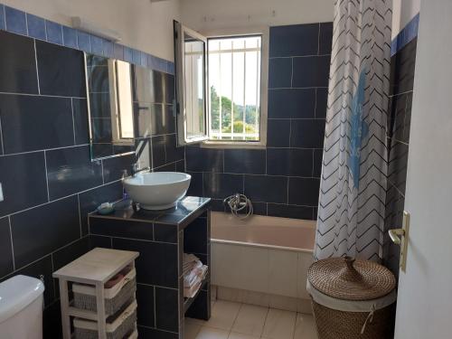 曼德琉-拉纳普勒Studio Golf Riviera - Axelle Loc'Appart的浴室铺有蓝色瓷砖,配有水槽和浴缸。
