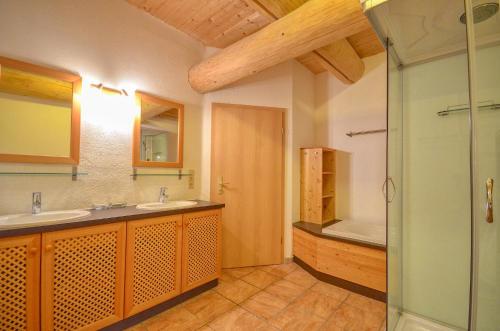 滨湖采尔Chalet Stabler - by Alpen Apartments的浴室配有2个盥洗盆、淋浴和浴缸。