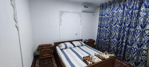 布哈拉Diyor Hostel的一间卧室配有床和蓝白色窗帘