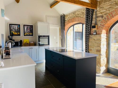 杜伦Contemporary Luxury Barn Conversion in County Durham的一间厨房,配有白色的橱柜和黑岛