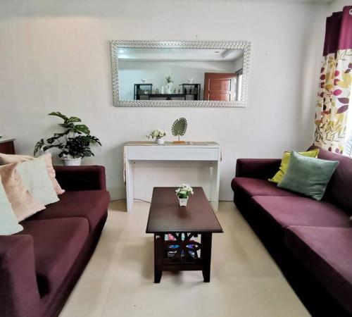 道伊斯2BR 2BT home with pool between Tagbilaran and Panglao的客厅配有两张紫色沙发和一张桌子