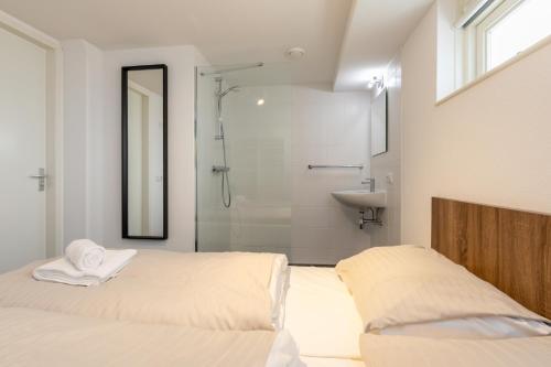 雷讷瑟Strandvilla 30 Renesse的一间带两张床、淋浴和盥洗盆的浴室