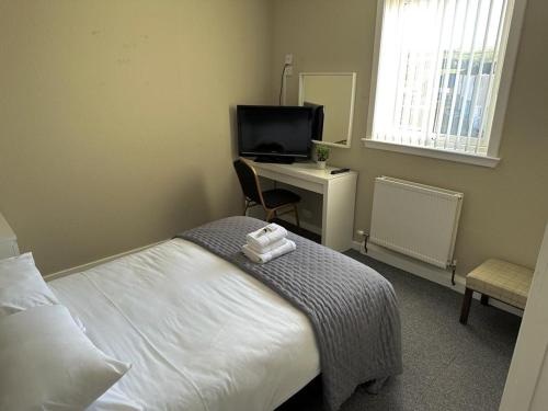 Sanquhar尼斯河谷旅馆的一间卧室配有一张床、一张书桌和一台电视