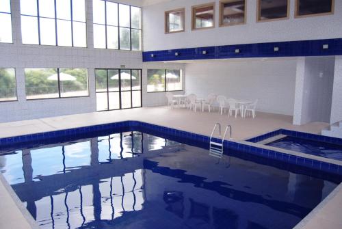 南卡希亚斯Sky Samuara Hotel Caxias do Sul的大楼内一个带桌椅的游泳池