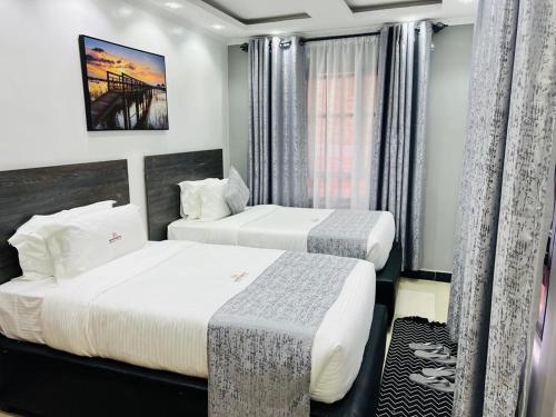 基苏木SR Apartments Milimani, Kisumu的配有窗户的酒店客房内的两张床