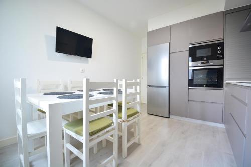 桑亨霍Apartamento en pleno centro de Portonovo, Sanxenxo的厨房配有桌椅和冰箱。
