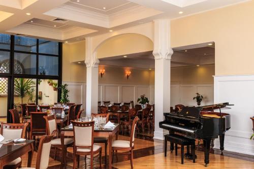 波苏阿莱格里马克斯广场酒店的餐厅的三角钢琴,配有桌椅