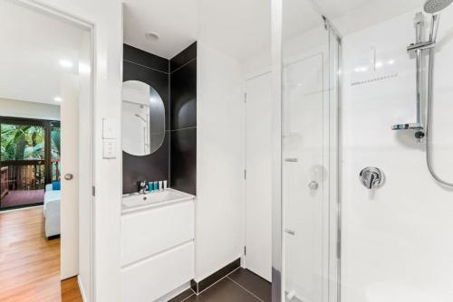 奥克兰A 1BR slice of Titirangi Heaven - WiFi - Netflix的白色的浴室设有水槽和淋浴。