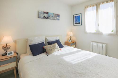 孔格林✦ Le Vol des Mouettes ✦ Port-Cogolin的卧室配有带蓝色枕头的大型白色床