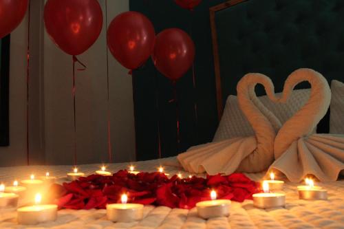 松索纳特hotel marsella的一组蜡烛和红色玫瑰,在床上和天鹅一起