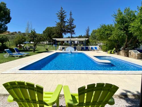 雷东多金塔奥法瓦酒店的一座房子旁的游泳池,配有两把绿色椅子