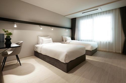 首尔The Connoisseur Residence Hotel的酒店客房配有两张床和一张书桌
