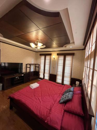 清迈Baan Weekday Chiang Mai的一间卧室配有一张红色大床和一台平面电视。