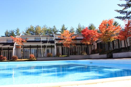 嬬恋村HOLIDAY VILLA Hotel & Resort KARUIZAWA的一座大房子,前面设有一个游泳池