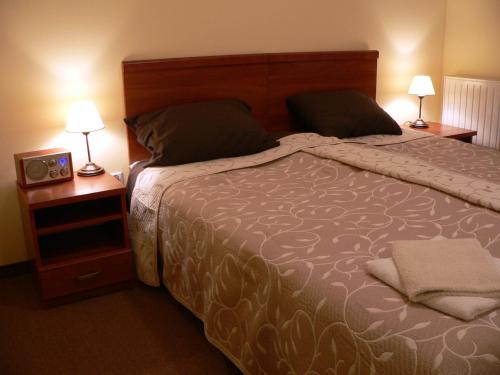 克雷尼察里拉宾馆的一间卧室配有一张床、两盏灯和一个时钟