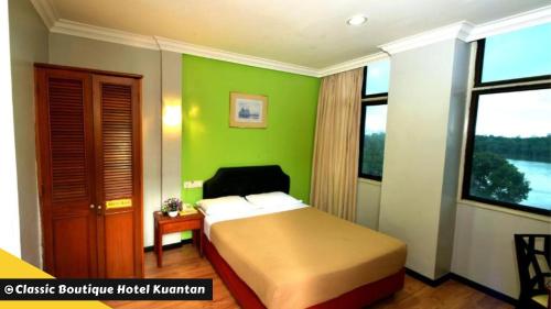 关丹Classic Boutique Hotel Kuantan的一间卧室设有一张床和绿色的墙壁