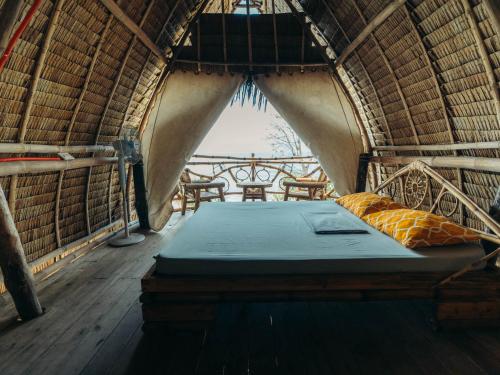 爱妮岛Isla - The Island Experience的茅草客房的一张床位,设有窗户