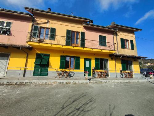 SovioreIl Giardino dei Pavoni的一座黄色和绿色的建筑,前面有椅子