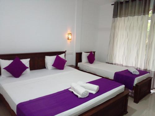 阿努拉德普勒Cumini Resort的紫白色客房的两张床