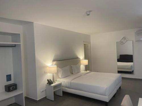 萨尔雷Oasis White Hotel的白色卧室配有床和镜子