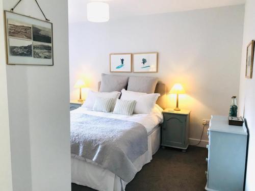 伍拉科姆5 Rockham - Luxury Apartment at Byron Woolacombe, only 4 minute walk to Woolacombe Beach!的一间卧室配有一张带白色床单和两盏灯的床。
