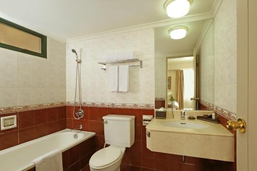 雅加达Aryaduta Suite Semanggi的浴室配有卫生间、浴缸和水槽。