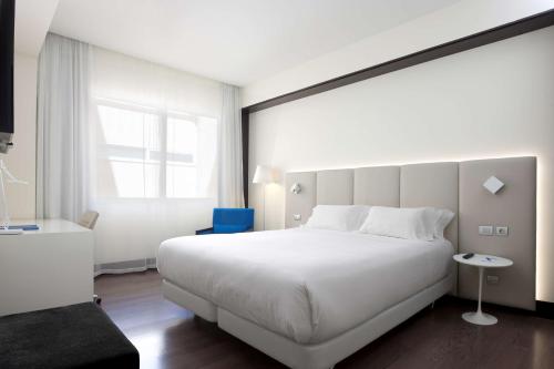 马德里NH马德里拉盖斯卡酒店的卧室设有一张白色大床和一扇窗户。
