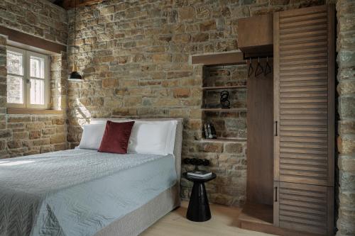 EllinikónLozArt Traditional Stone House的一间卧室设有一张床和砖墙