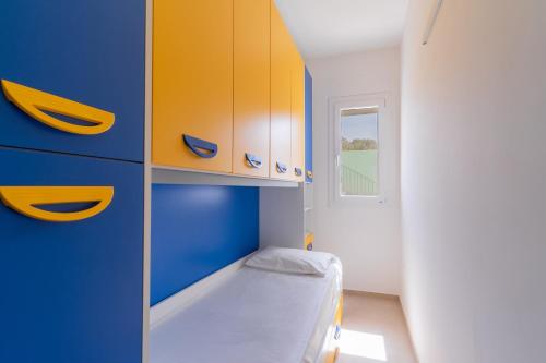 托雷圣乔万尼乌Appartamenti Li Paduli的一间设有蓝色和黄色橱柜的小卧室