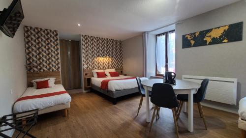 Saint-PoncyLogis Hôtel Auberge de l'Allagnonette的酒店客房带两张床和一张桌子以及椅子。