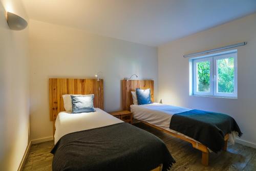 卡斯卡伊斯必库达乡村民宿的一间卧室设有两张床和窗户。