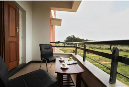德瓦纳哈利-班加罗尔ZIONS HOTEL AND APERTMENT的客房设有带桌椅的阳台。