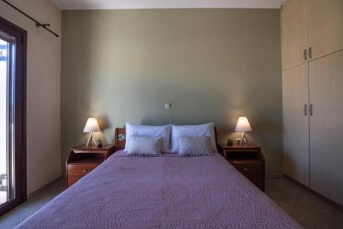 基萨莫斯Terpsis House的一间卧室配有一张带紫色床单和两盏灯的大床