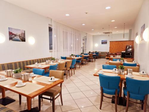 美因河畔法兰克福Trip Inn Hotel Minerva Frankfurt的餐厅设有木桌和蓝色椅子