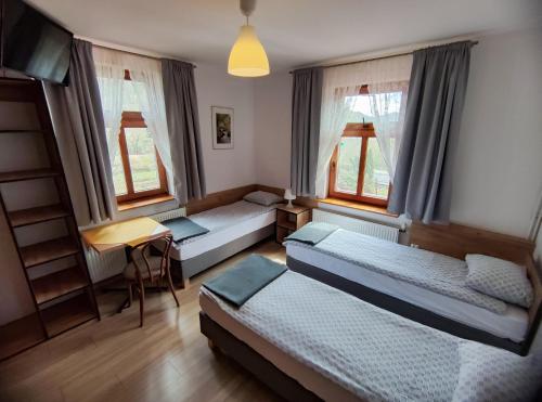 鲁特罗Zajazd PTTK Pod Roztoką的一间卧室配有两张床、一张桌子和两个窗户。